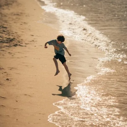 Young boy jumping joyfully over the waves of the sea